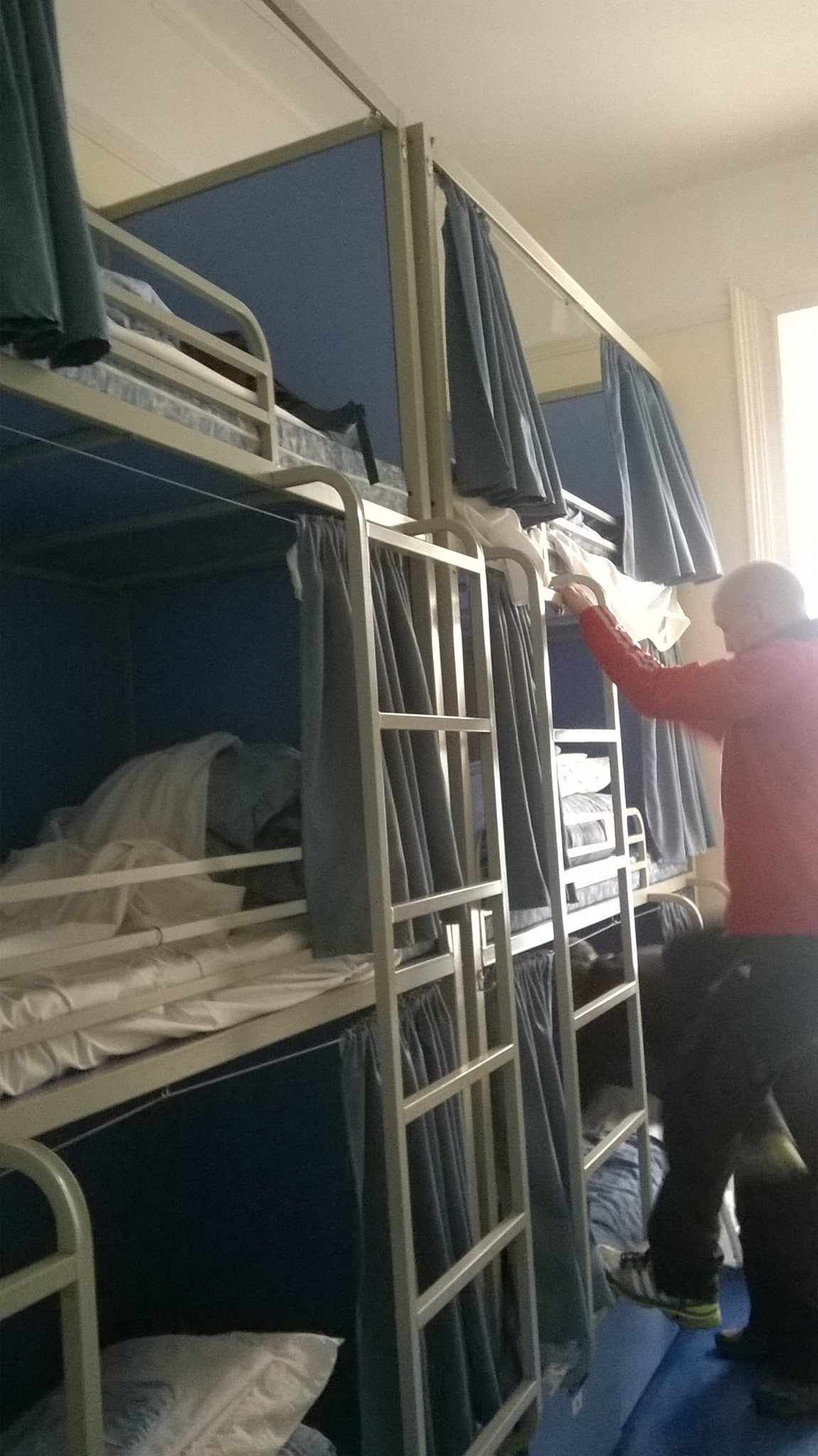 DD inspects his top bunk in the hostel dorm. 